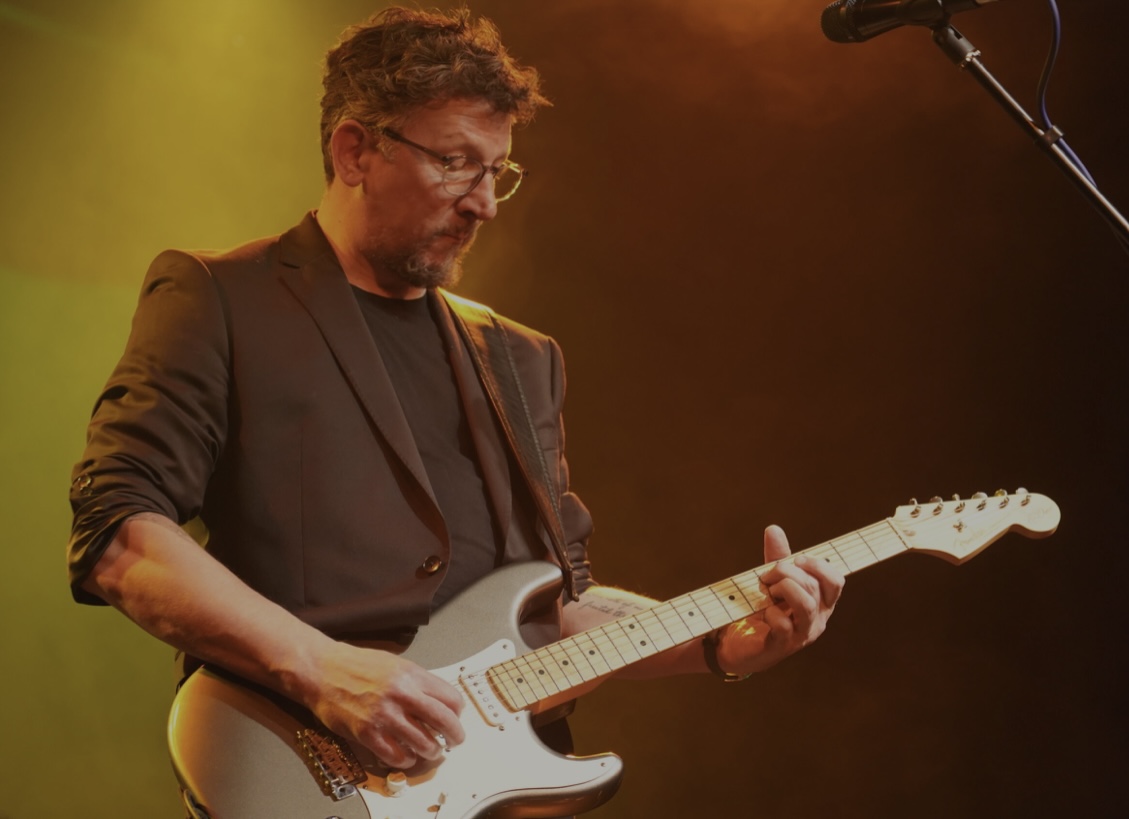 Benny playing his Stratocaster under warm amber stage lights